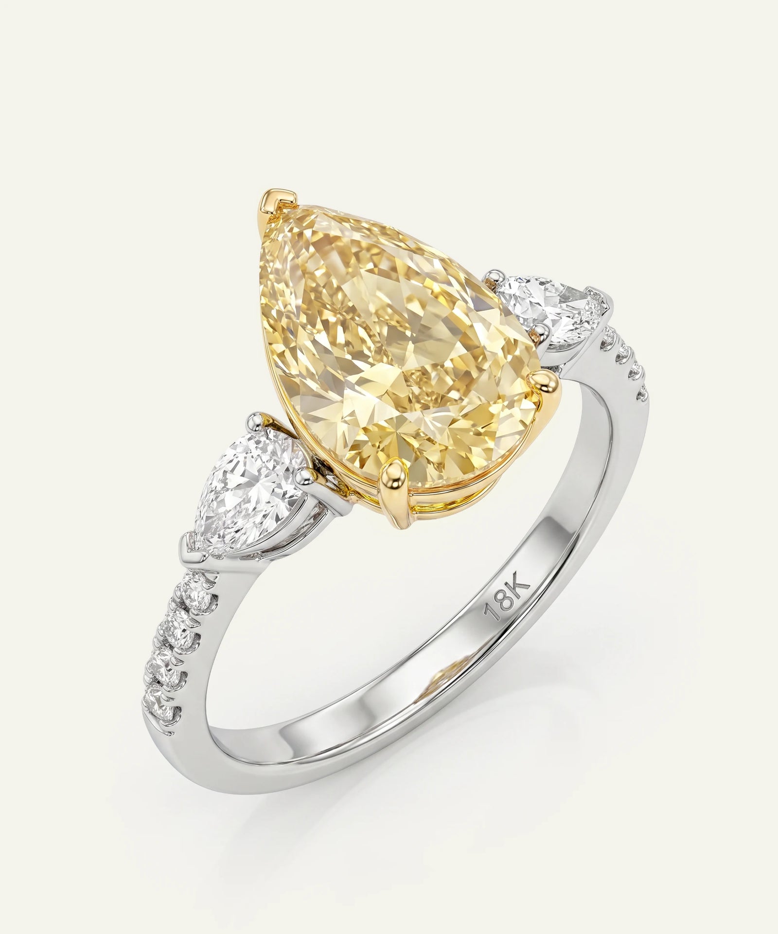 Gold pear-shaped diamond ring with white gemstones on a light gray background