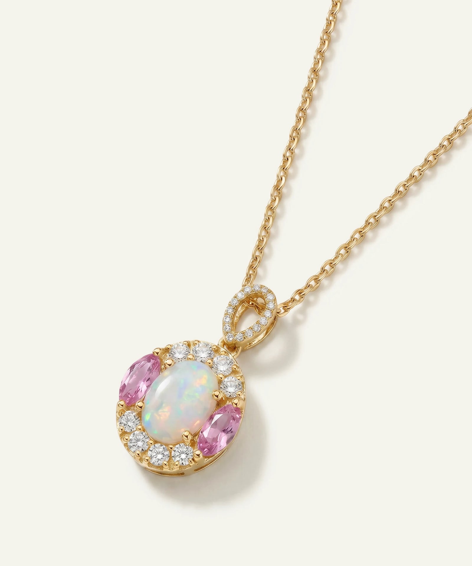 Gold necklace with an opal and pink gemstone pendant on a white background