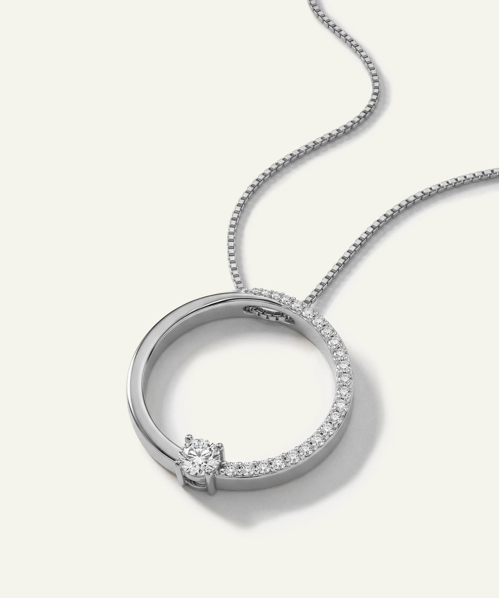 Silver necklace with a circular pendant on a white background