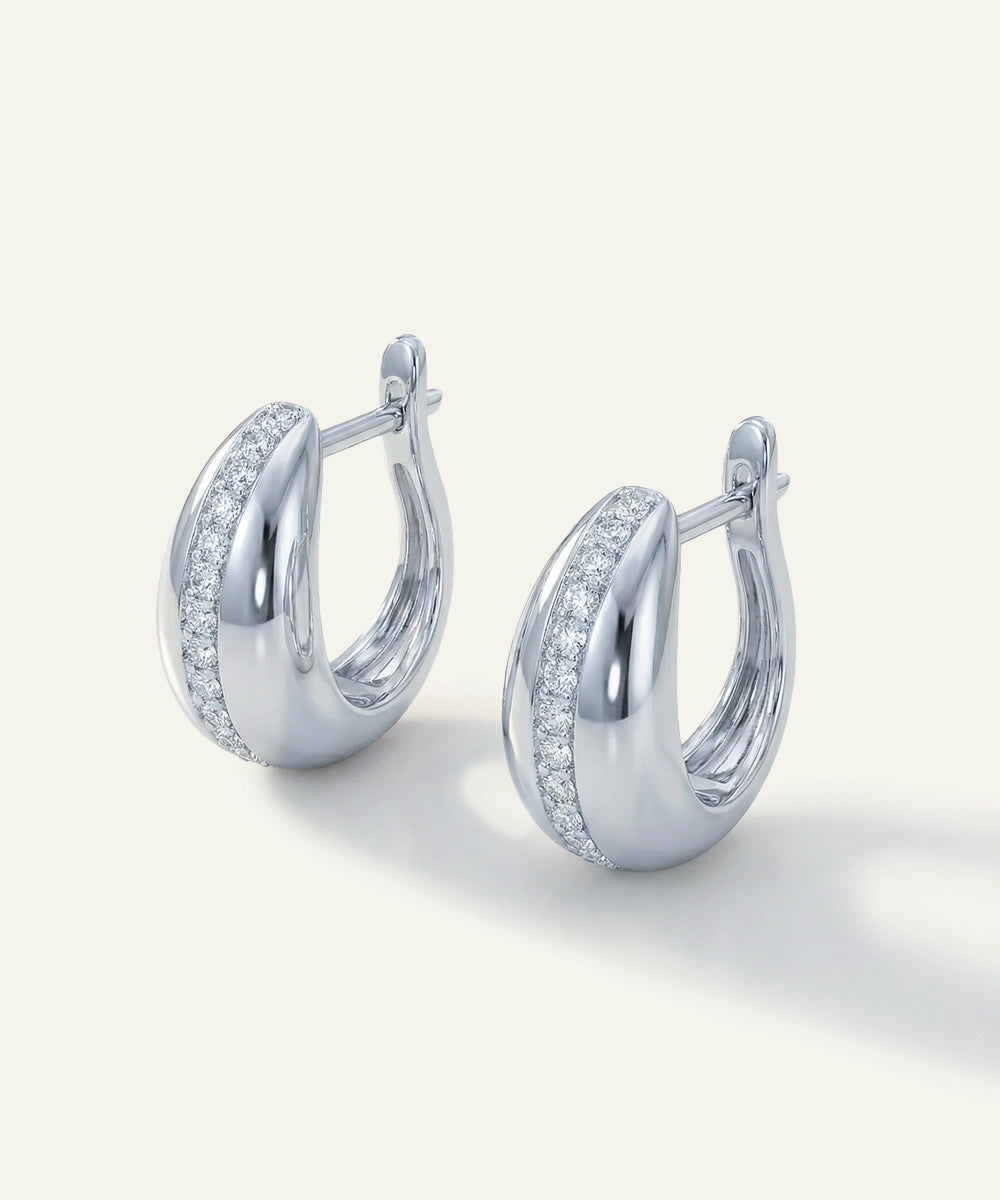 Pair of silver hoop earrings with clear gemstones on a light gray background