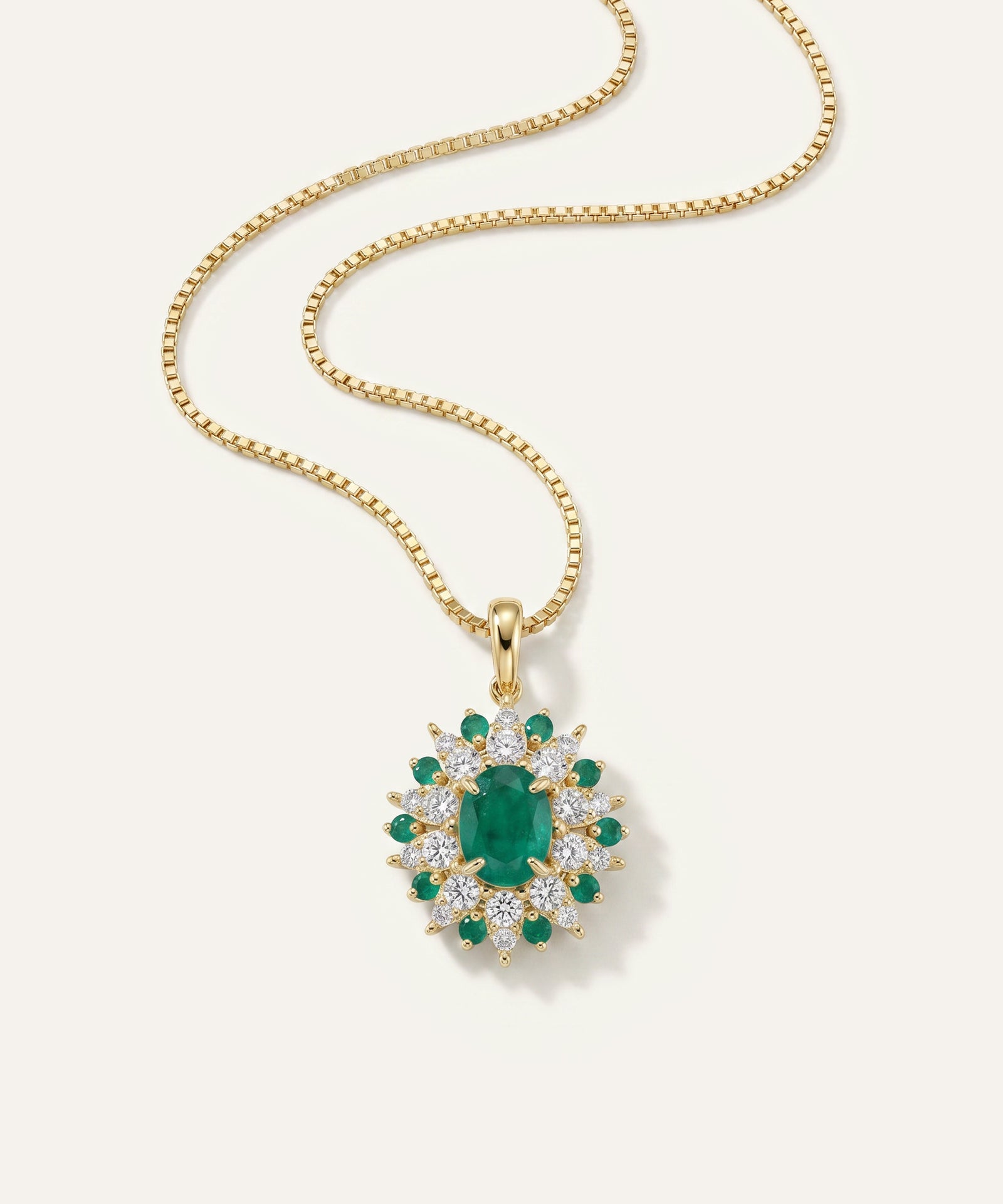 Gold necklace with a green gemstone pendant on a white background