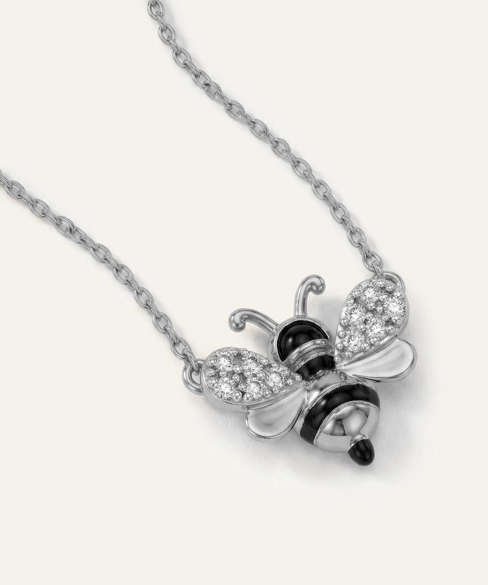 Silver bee-shaped pendant necklace with black and clear gemstones on a white background