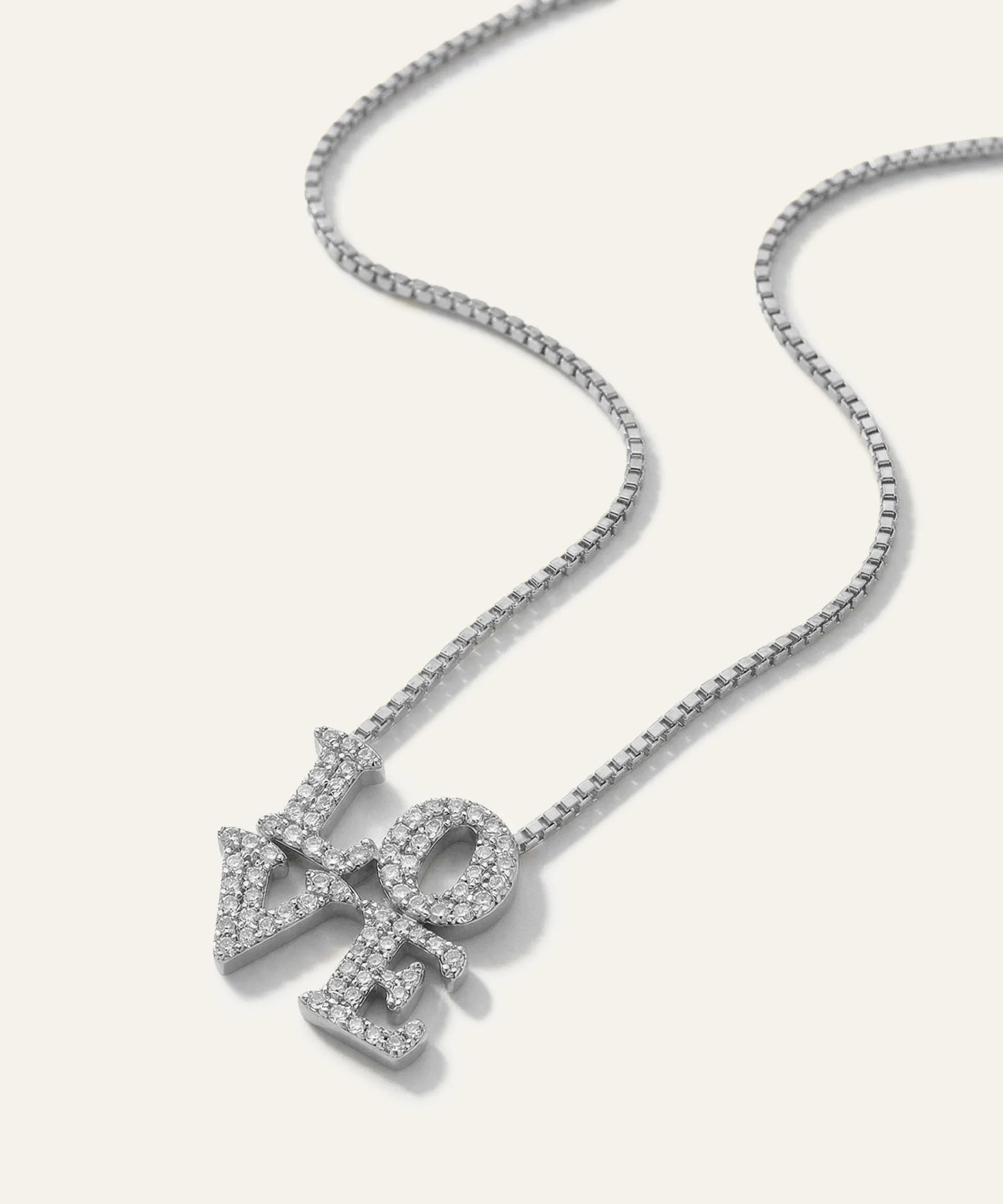 Silver necklace with a diamond-encrusted pendant on a light gray background