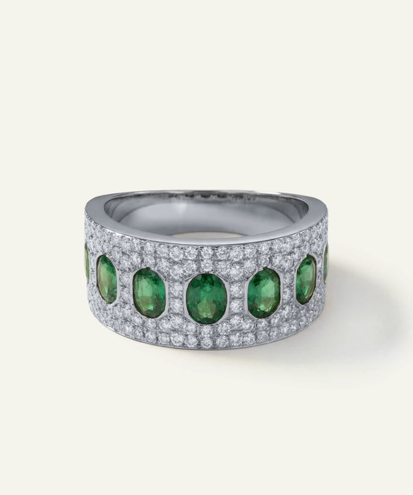 Silver ring with green gemstones on a white background