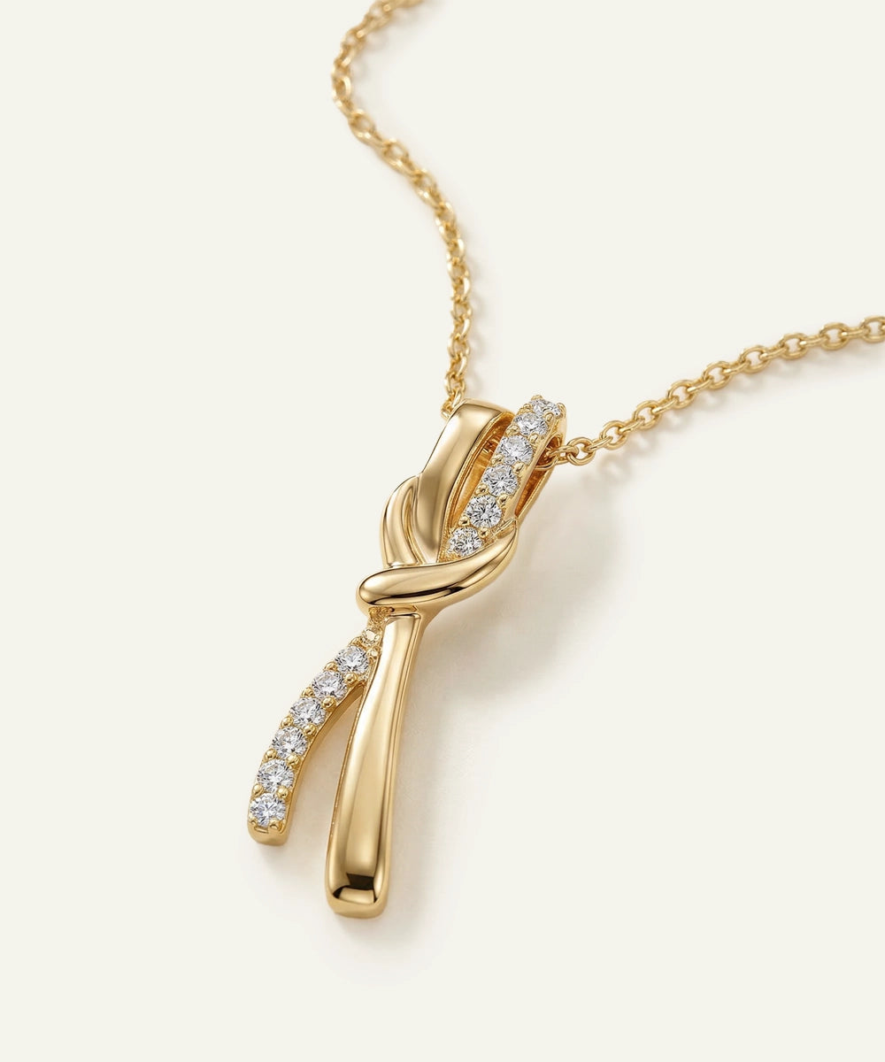 Gold necklace with a diamond pendant on a light beige background