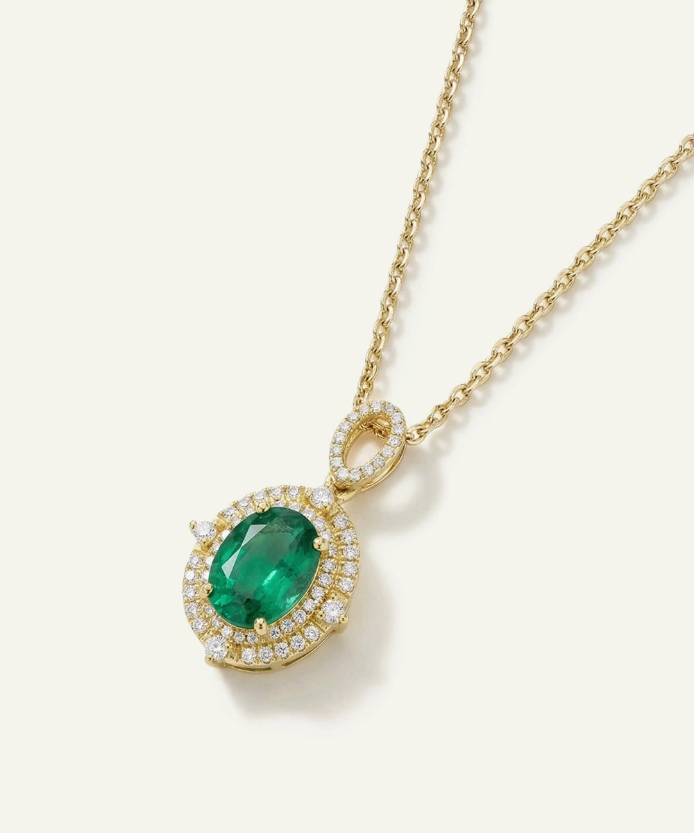 Gold necklace with a green gemstone pendant on a white background