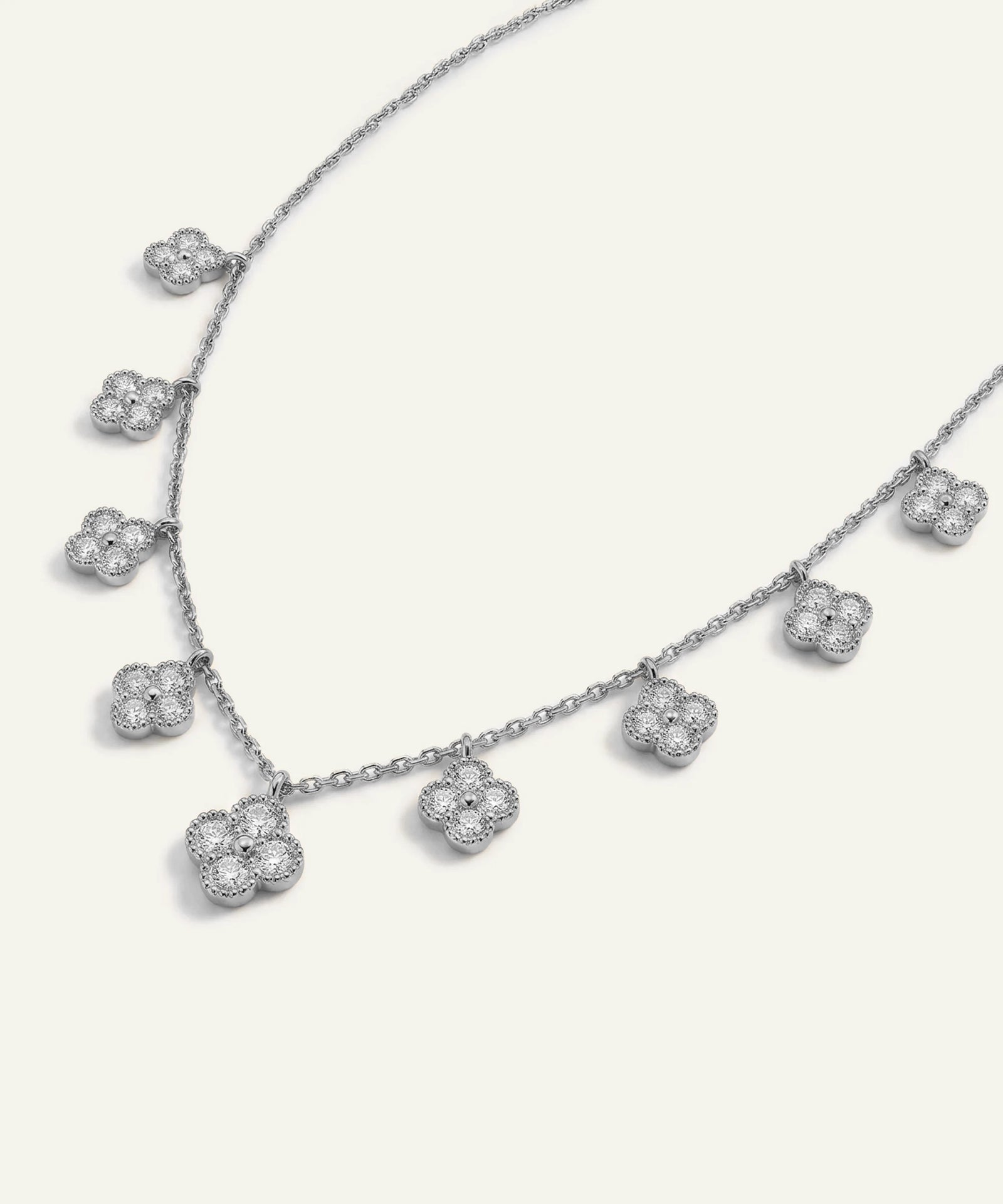 Silver necklace with floral pendant on a light gray background