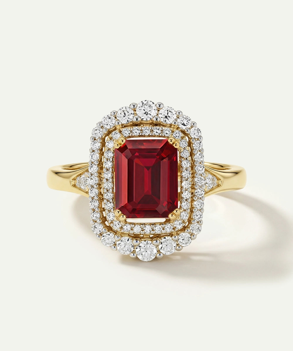 Gold ring with a red gemstone and diamond accents on a white background