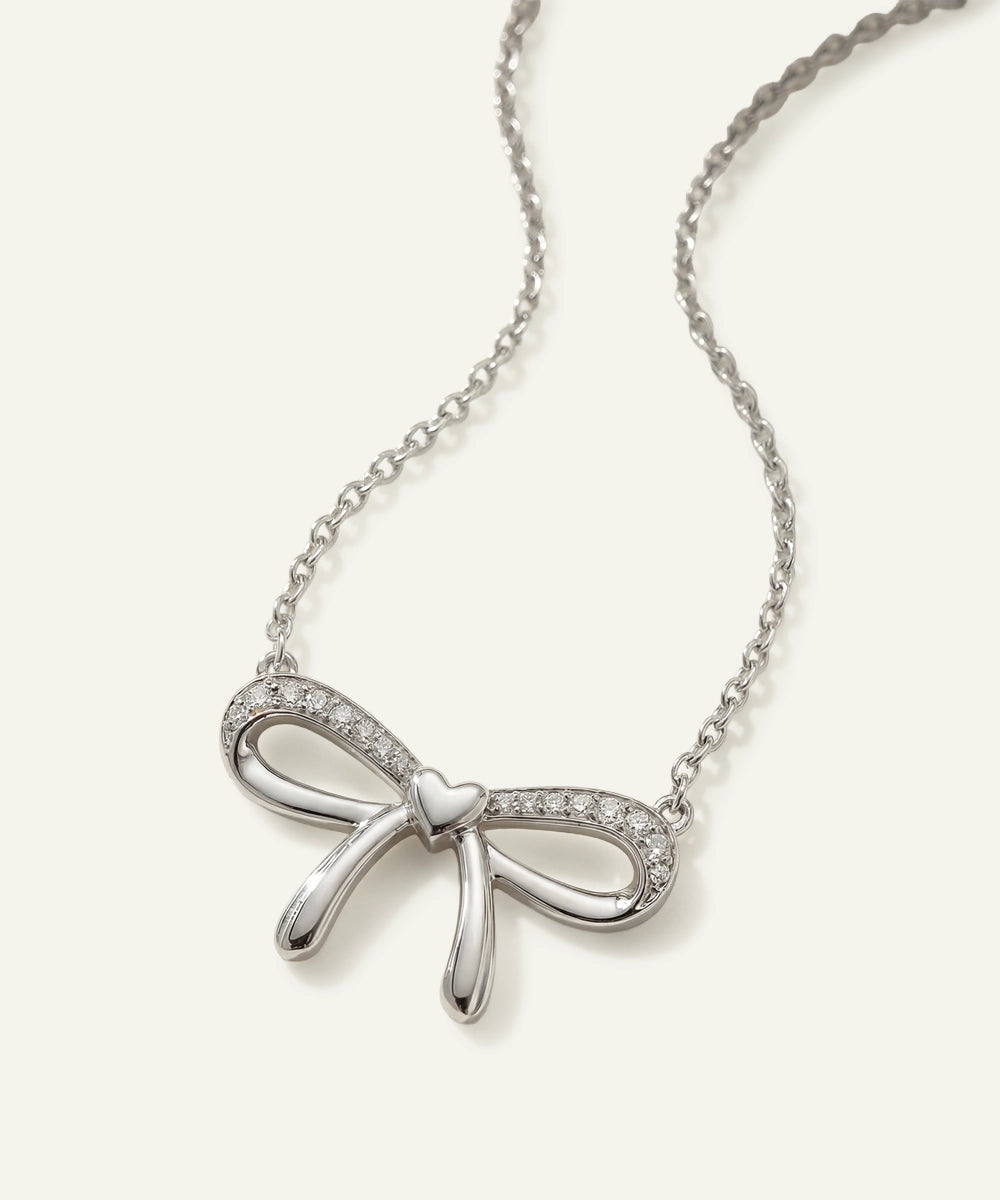 Silver bow-shaped pendant necklace on a white background
