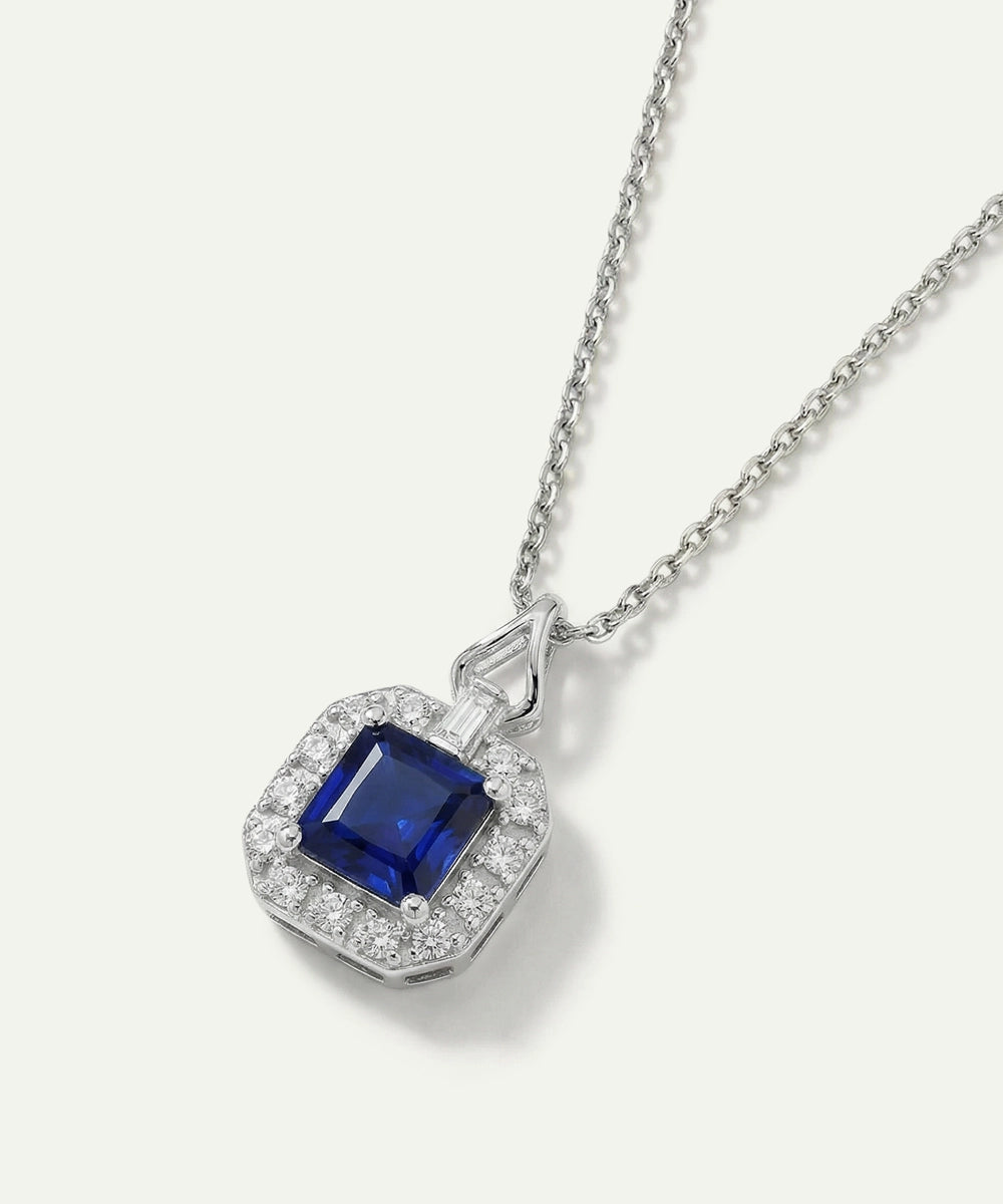Silver necklace with a blue gemstone pendant on a white background