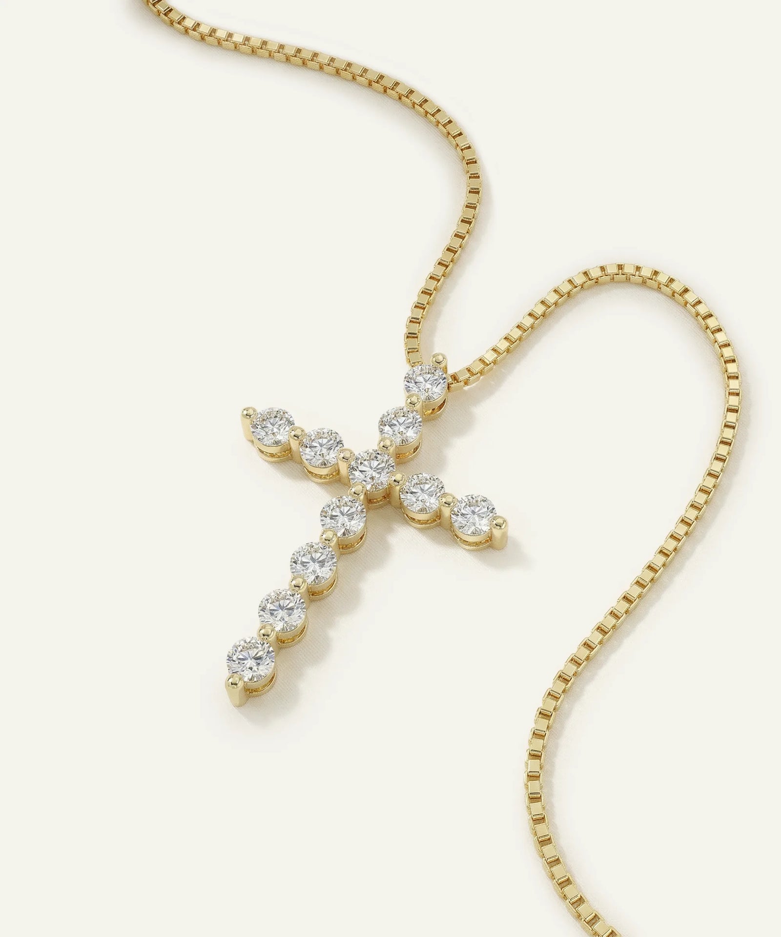 Gold necklace with a diamond cross pendant on a white background