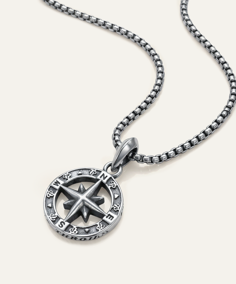 Silver compass pendant necklace on a white background