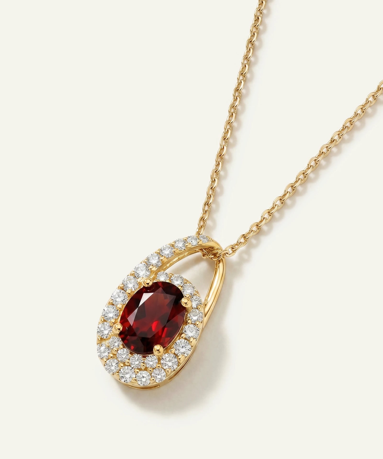 Gold necklace with a red gemstone pendant on a white background