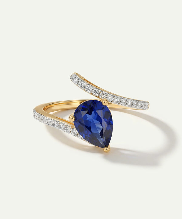 Gold ring with a blue gemstone and diamond accents on a white background