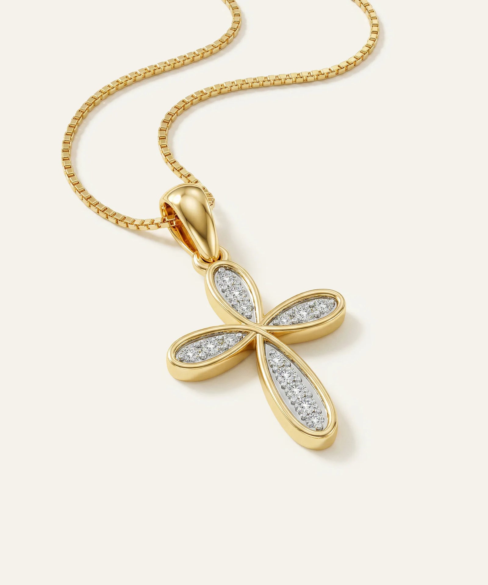 Gold cross pendant with diamond accents on a white background
