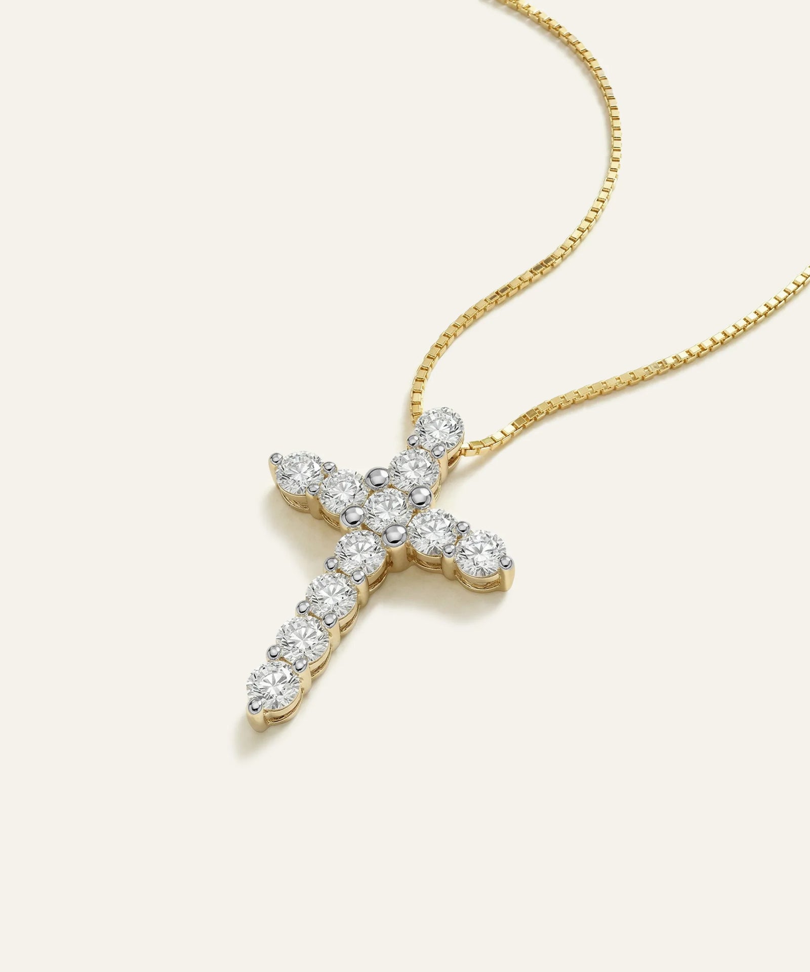 Gold cross necklace with diamond accents on a white background