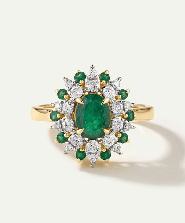 Gold ring with emerald and diamond stones on a white background