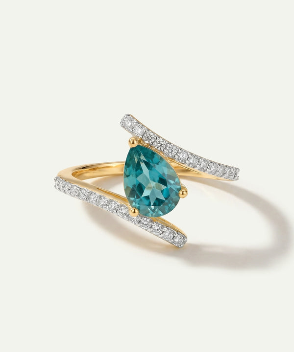 Gold ring with a pear-shaped blue gemstone and diamond accents on a white background