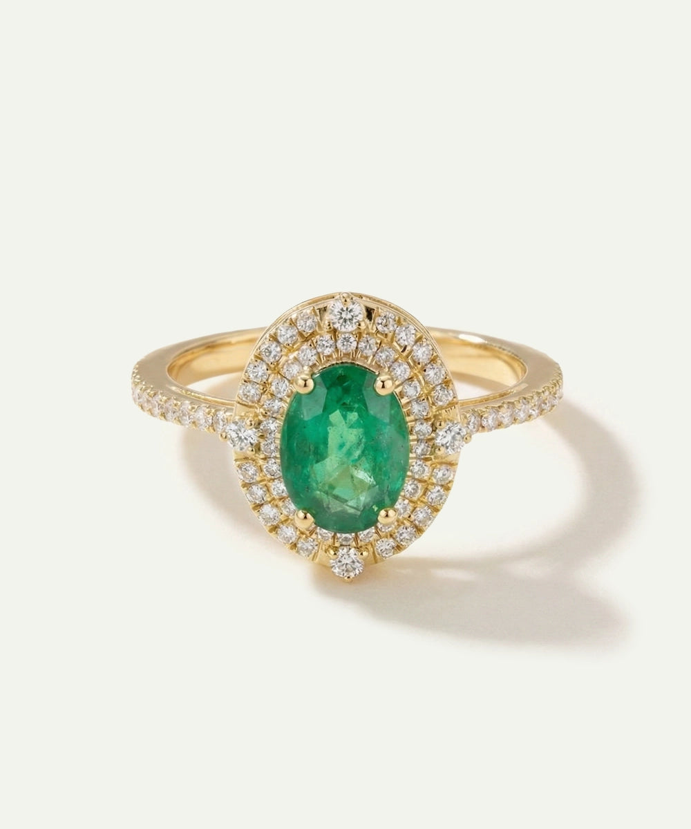 Gold ring with a green gemstone and diamond accents on a white background