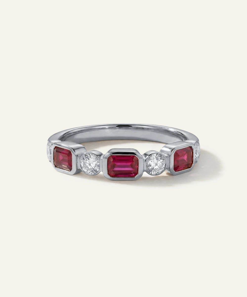 Silver ring with red gemstones and clear stones on a white background