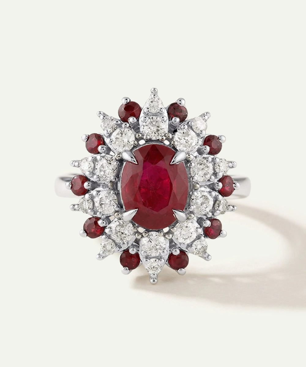 Elegant ring with a central red gemstone surrounded by smaller red and clear stones on a light gray background