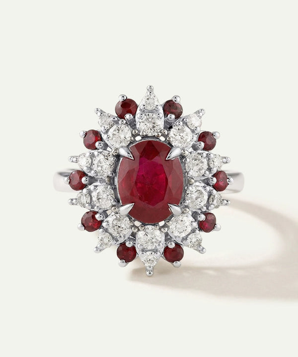 Elegant ring with a central red gemstone surrounded by smaller red and clear stones on a light gray background