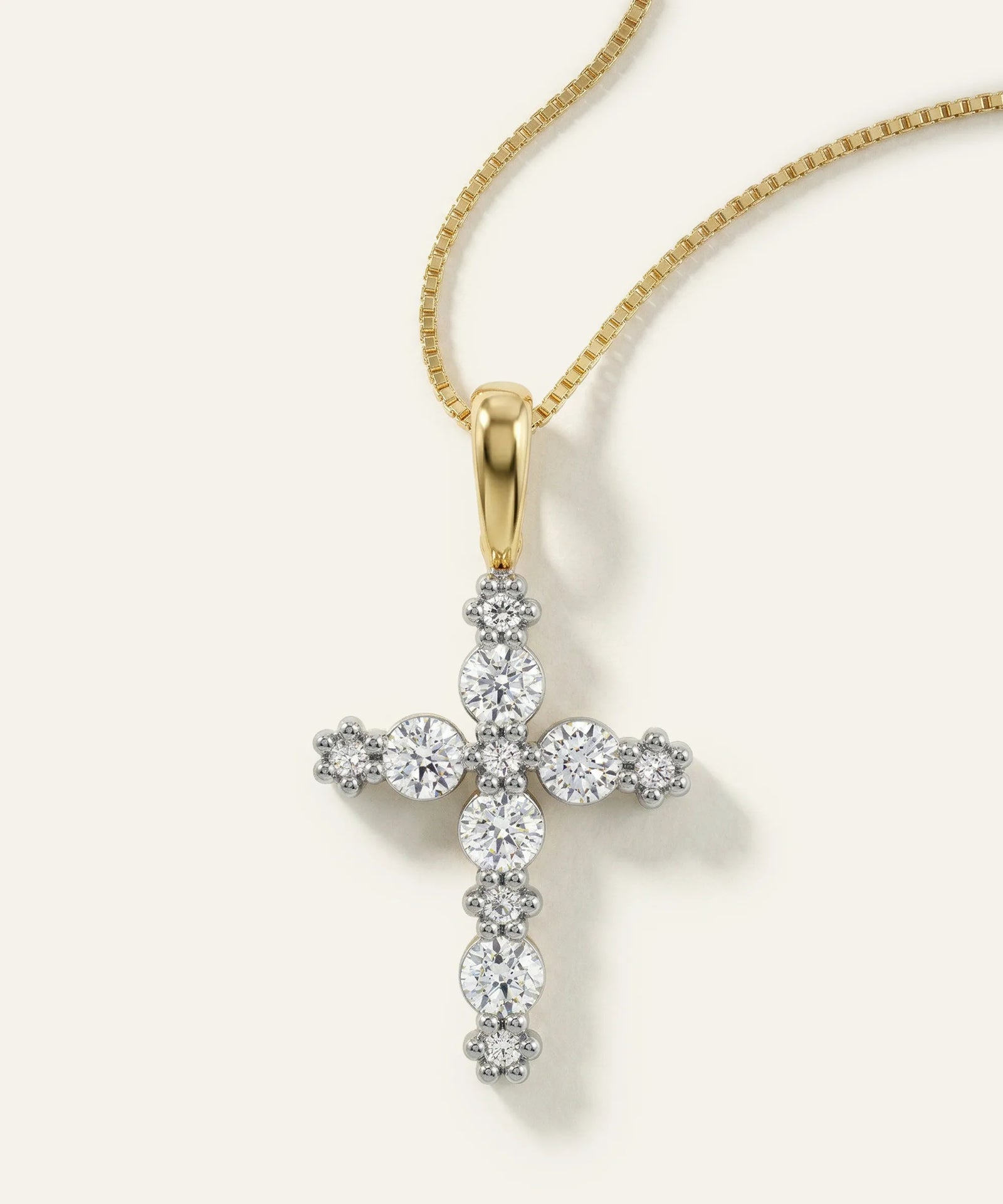 Gold cross pendant with diamonds on a gold chain against a white background