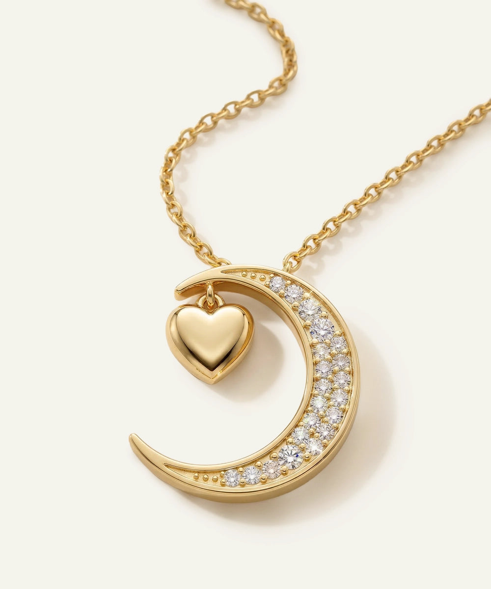 Gold necklace with a heart and crescent moon design on a white background