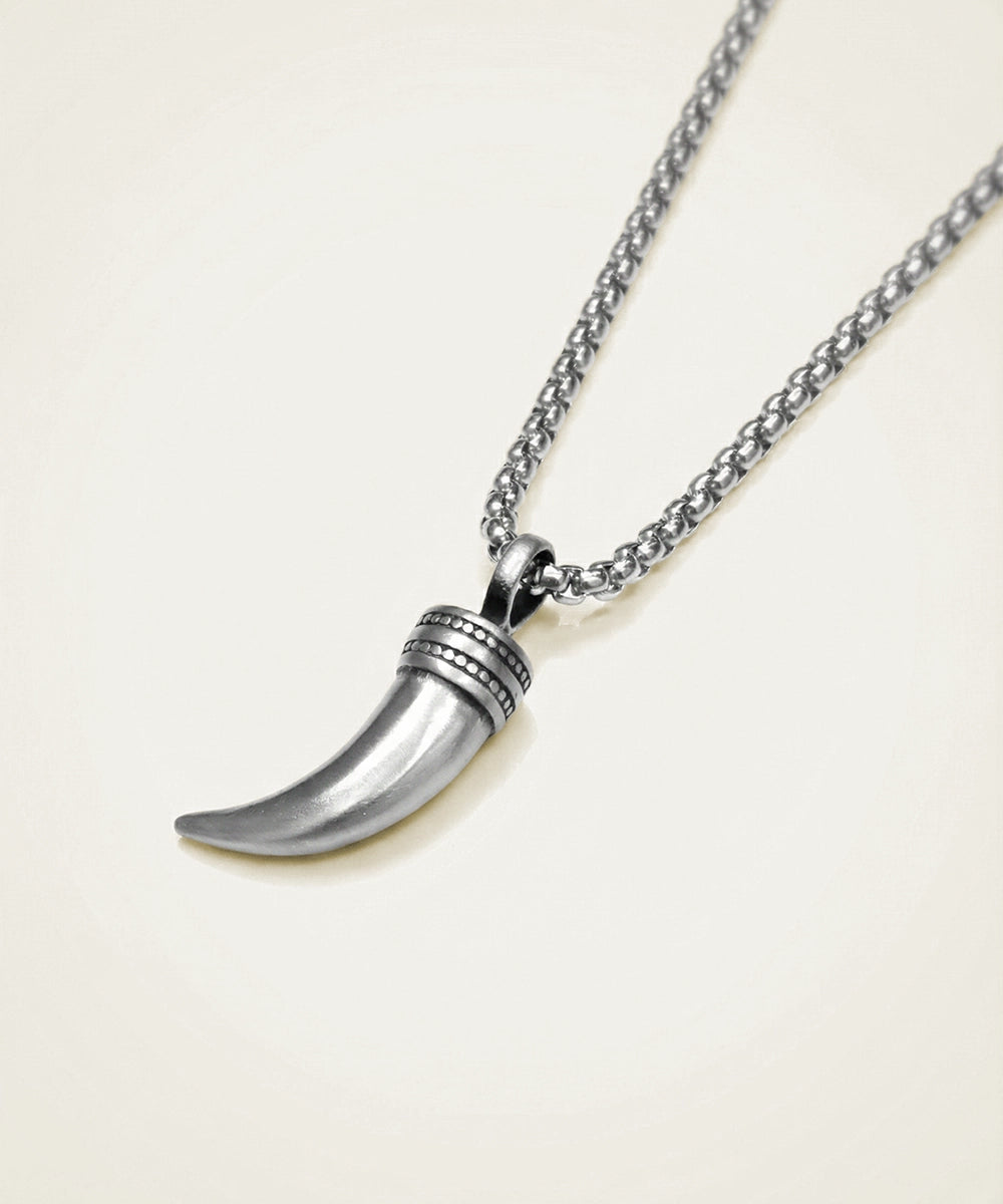 Silver necklace with a tusk pendant on a light beige background
