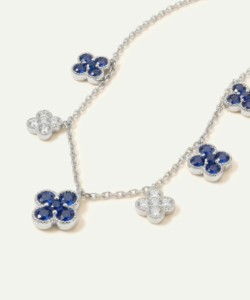Silver necklace with blue flower-shaped pendants on a white background