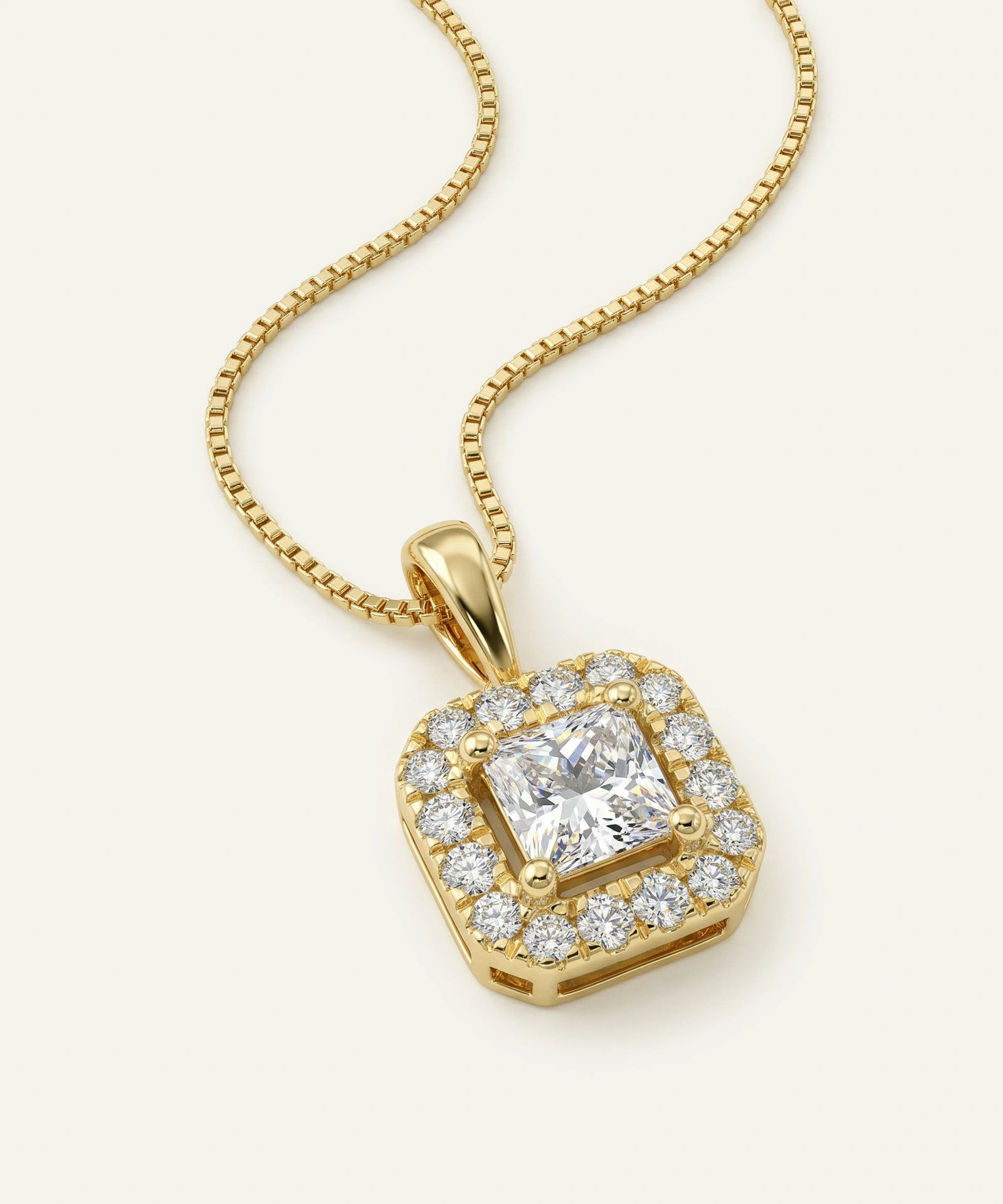 Gold necklace with a heart-shaped diamond pendant on a light beige background