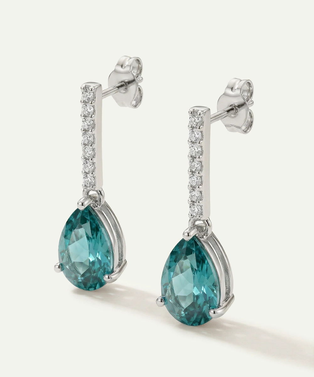 Pair of earrings with blue gemstones and diamond accents on a white background