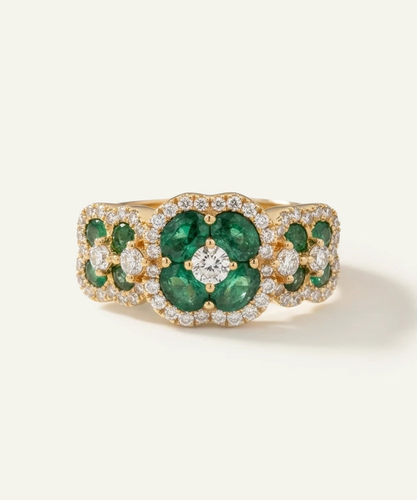 Gold ring with emeralds and diamonds on a light beige background