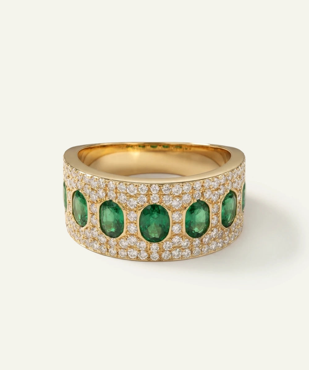 Gold ring with emeralds and diamonds on a white background