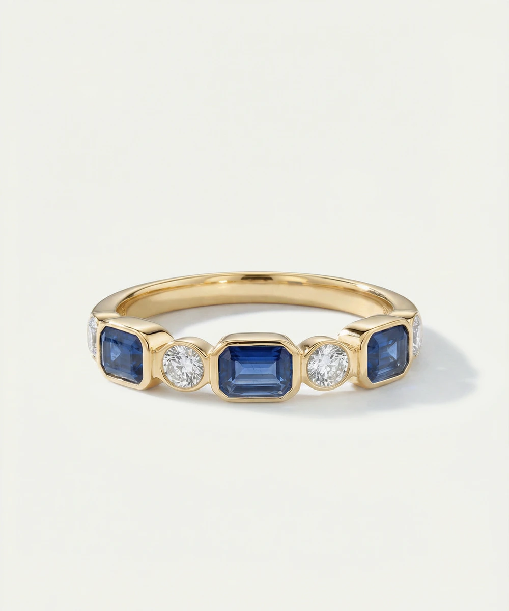 Gold ring with blue gemstones and diamonds on a light gray background