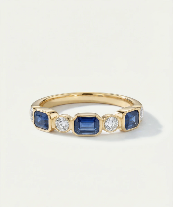 Gold ring with blue gemstones and diamonds on a light gray background