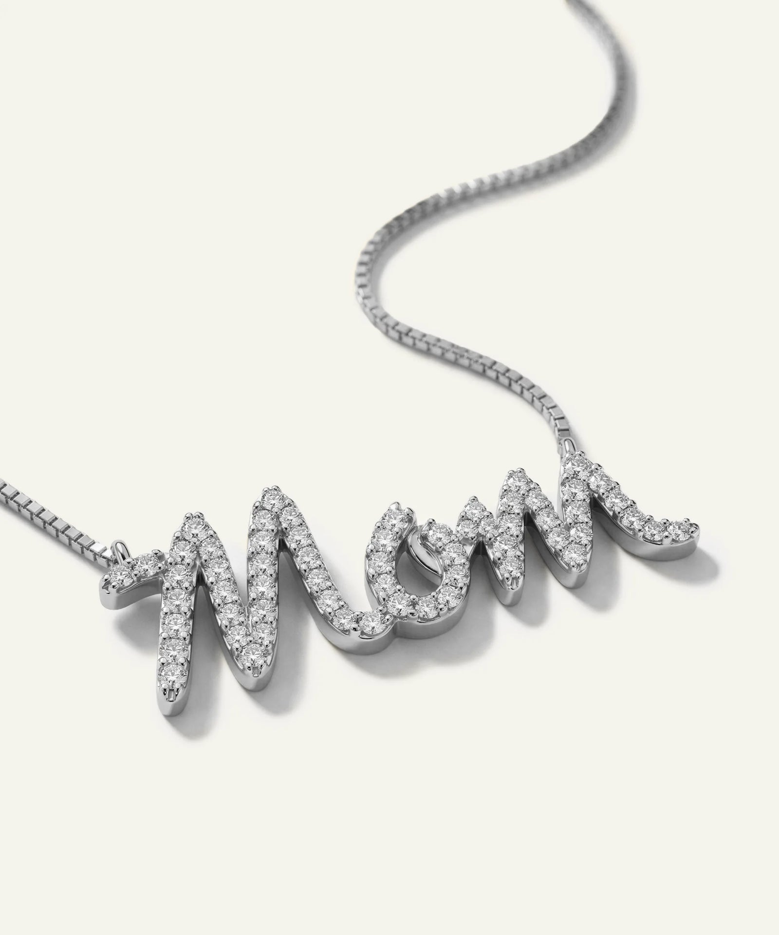 Silver 'Mom' necklace with diamonds on a white background
