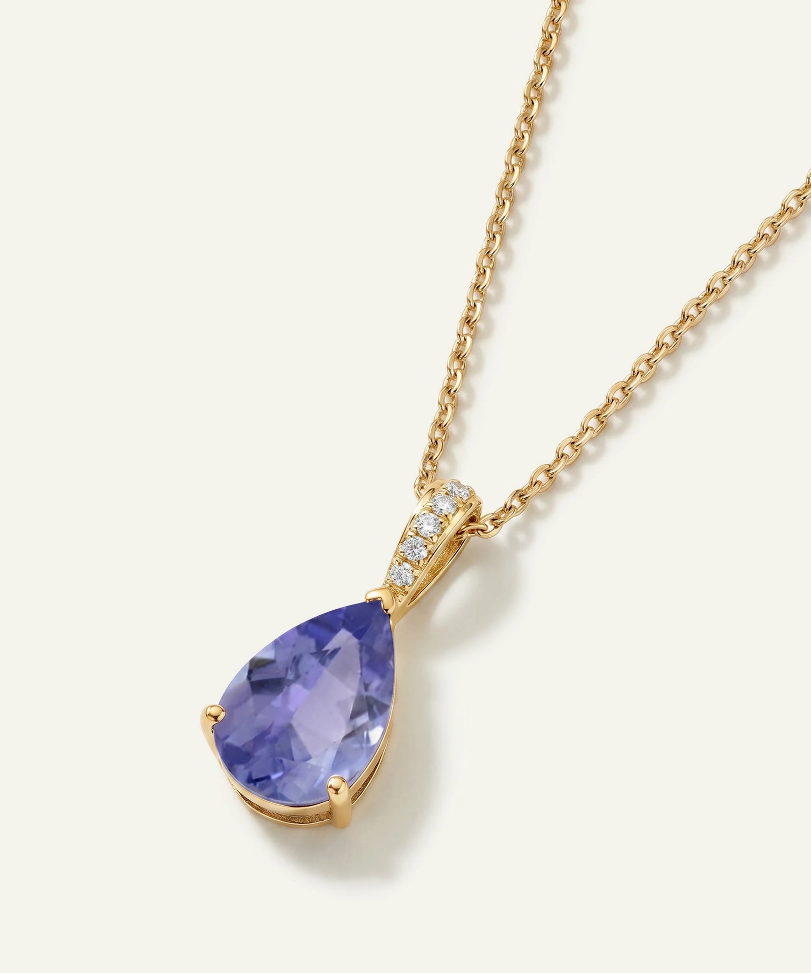 Gold necklace with a purple teardrop pendant on a white background
