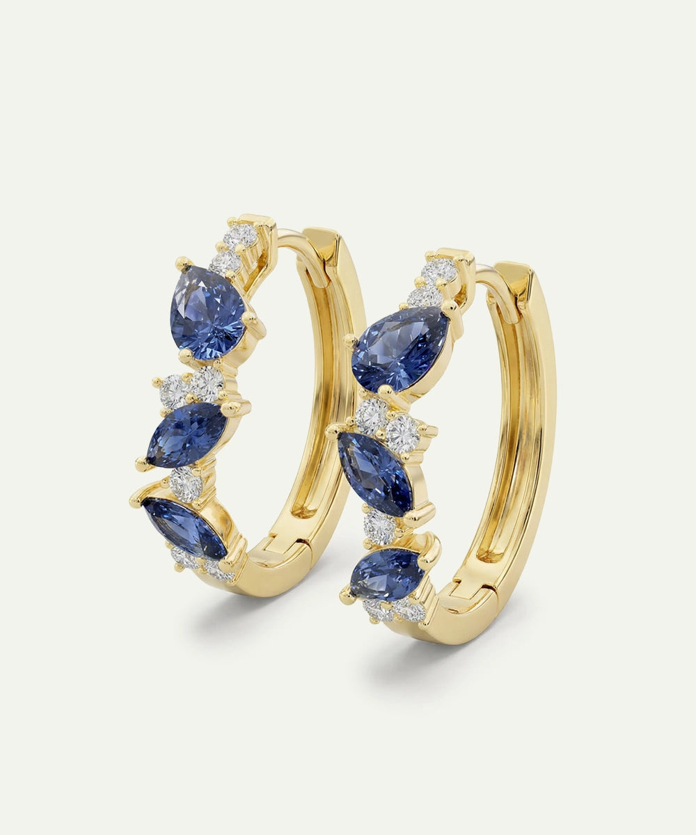Gold hoop earrings with blue gemstones on a white background