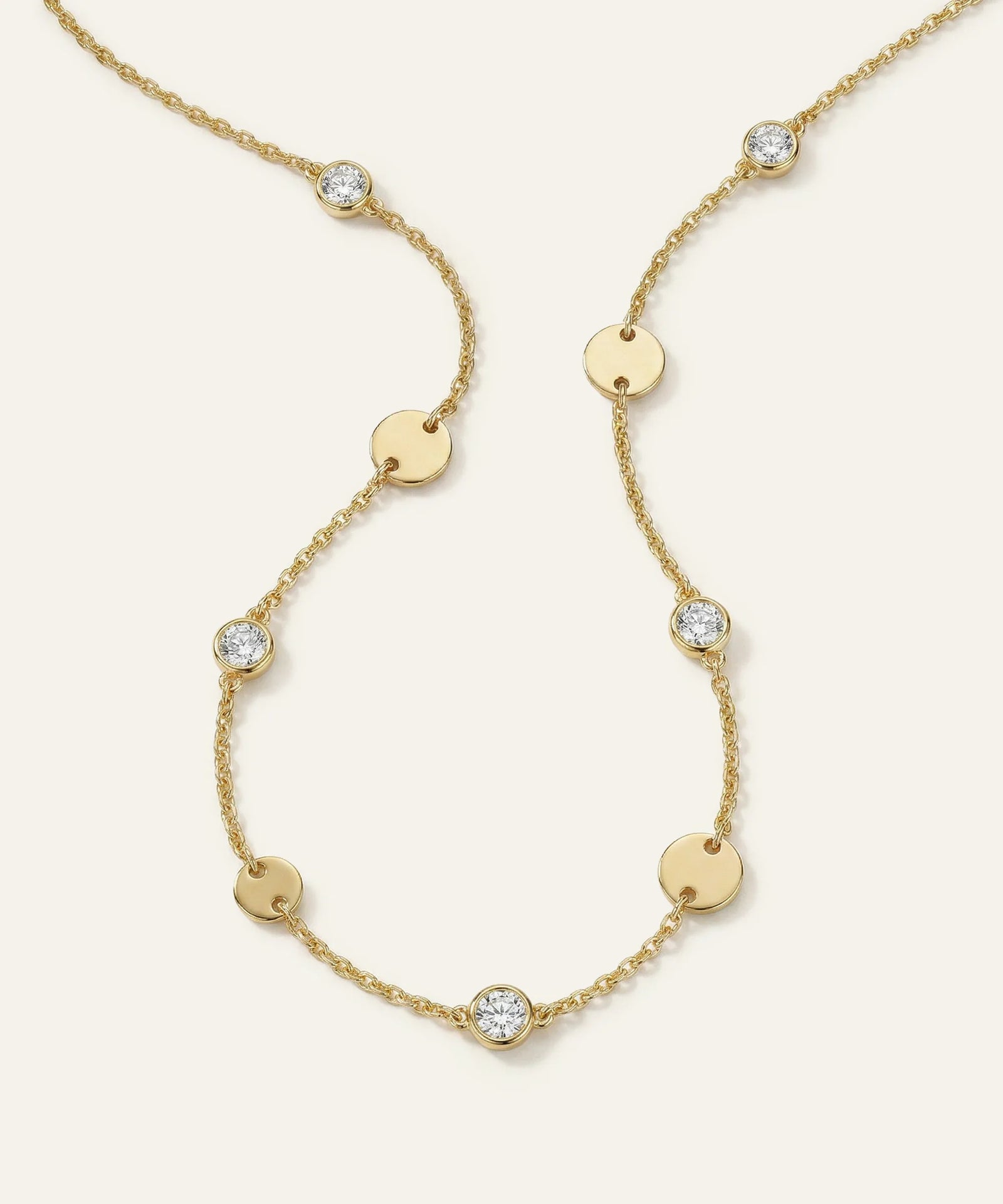Gold necklace with diamond accents on a light beige background