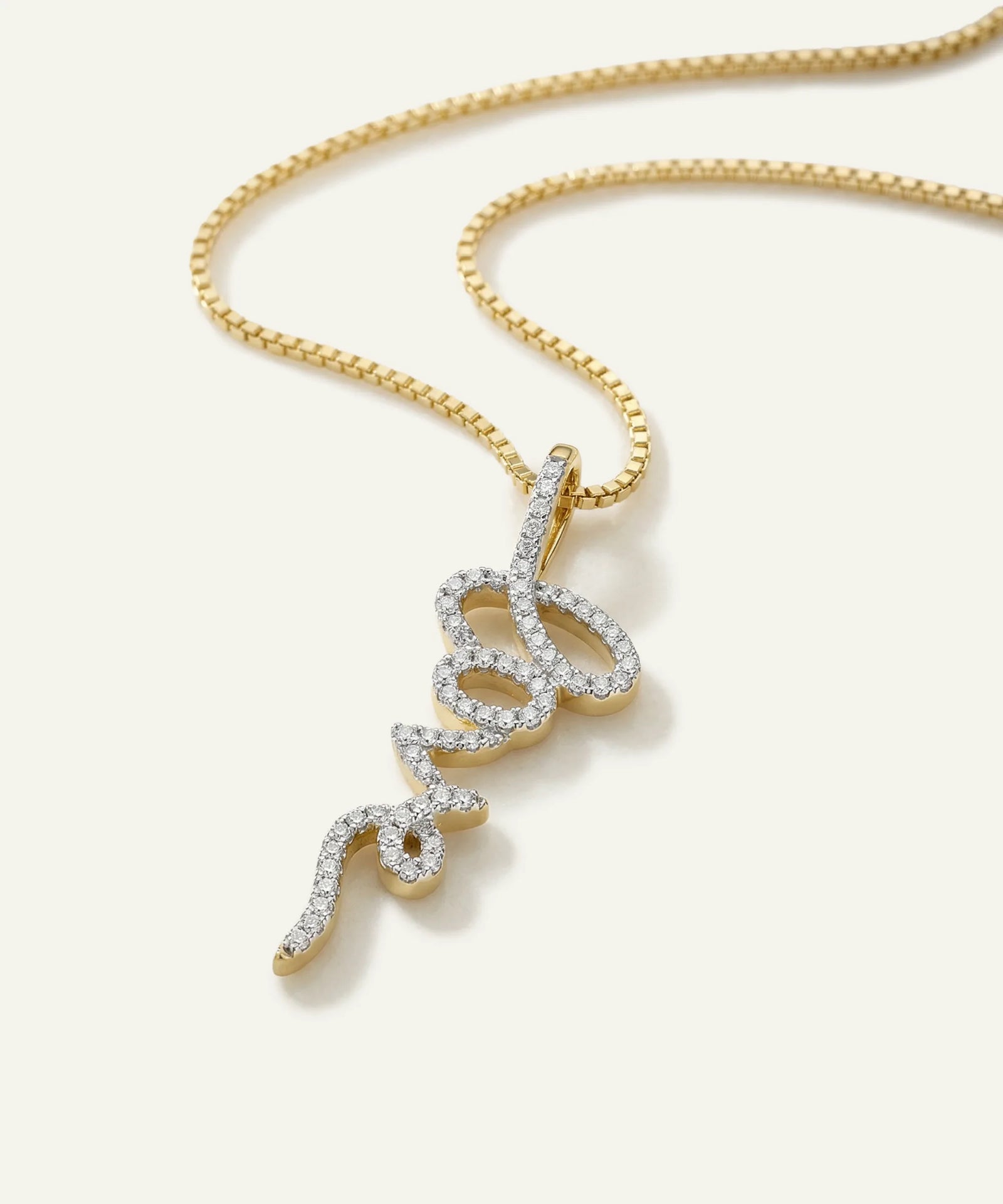 Gold necklace with a diamond-encrusted pendant on a white background