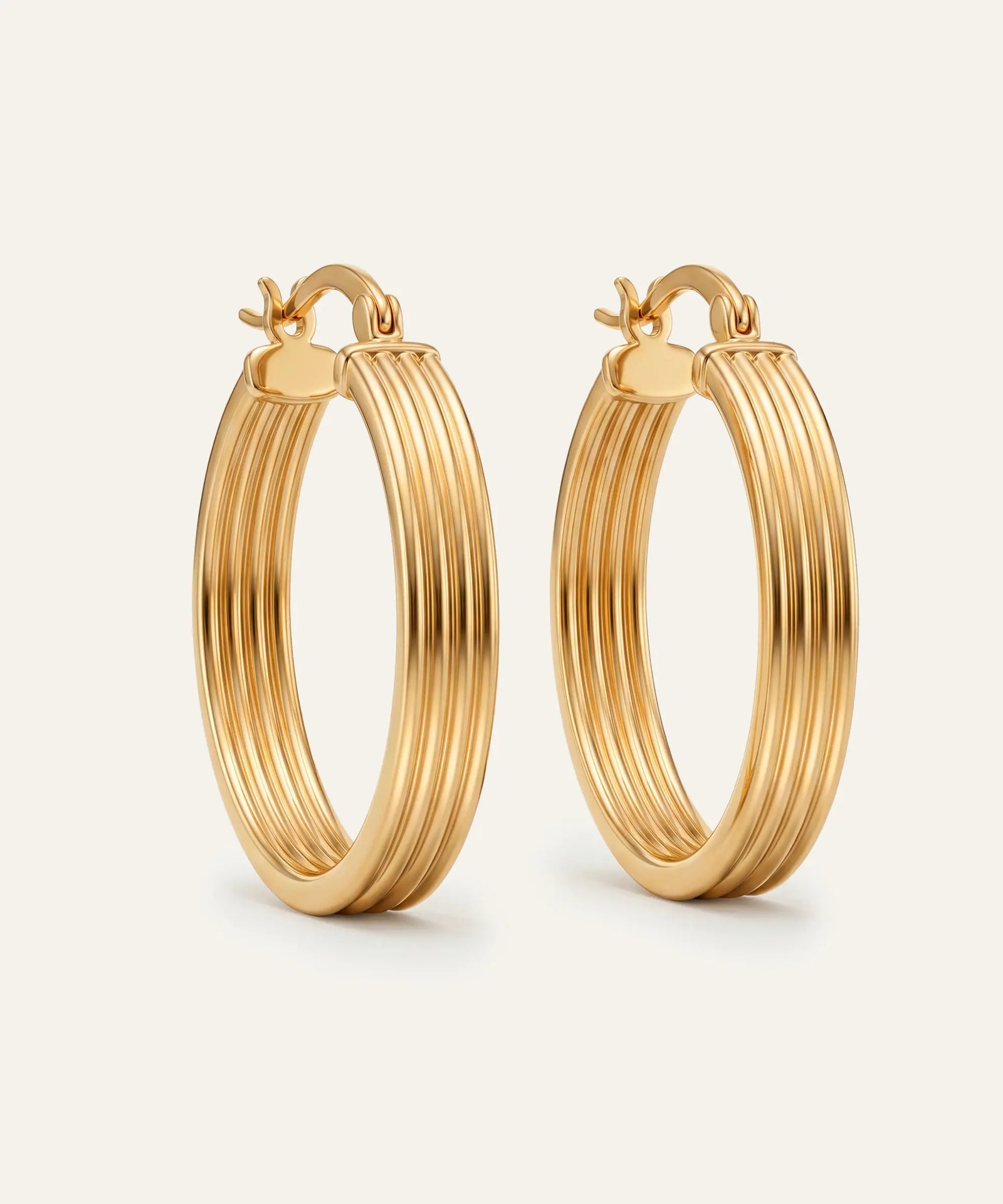 Gold hoop earrings on a light beige background