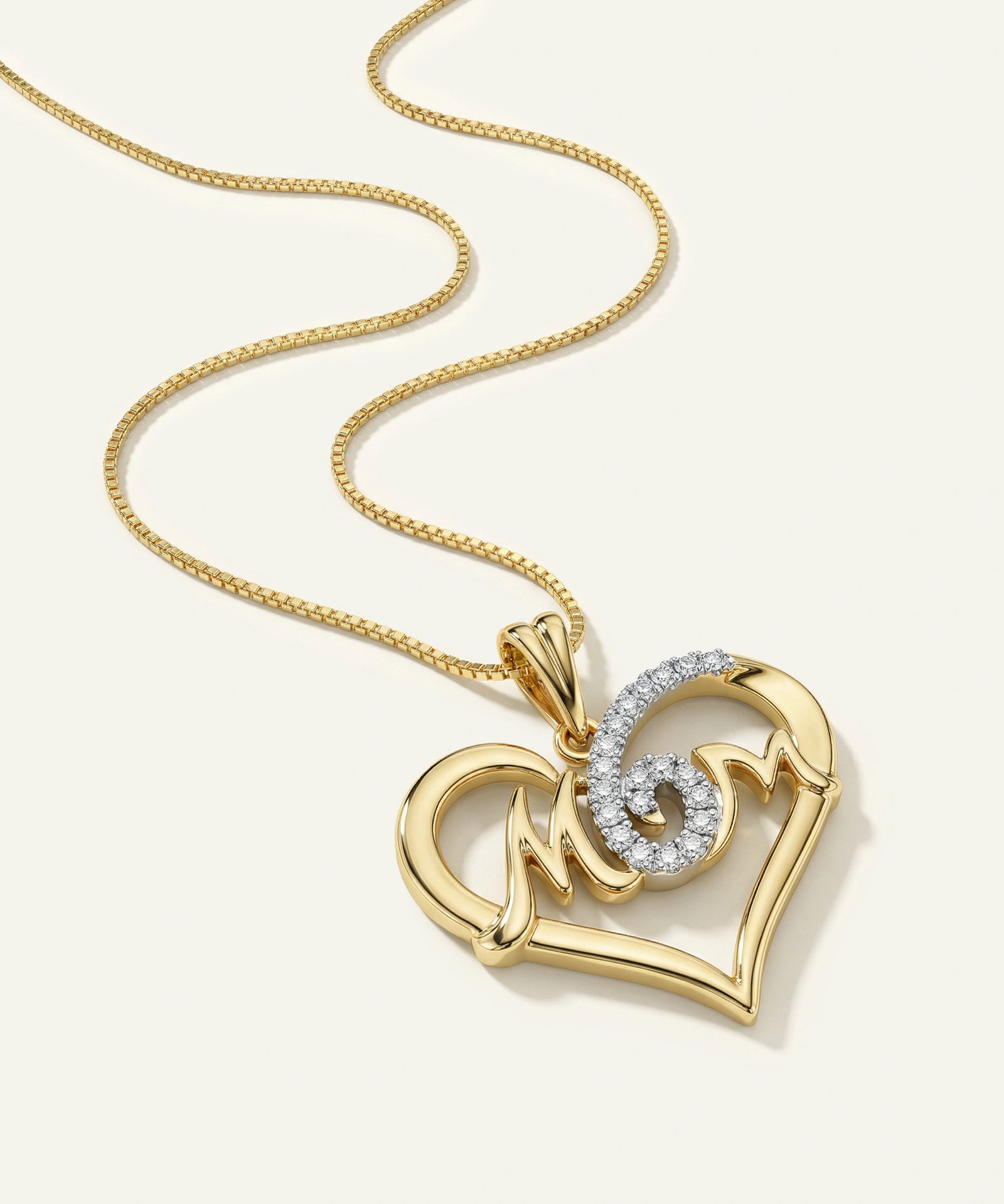 Gold necklace with a heart-shaped pendant on a light beige background