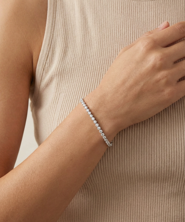 Silver bracelet on a wrist against a neutral background