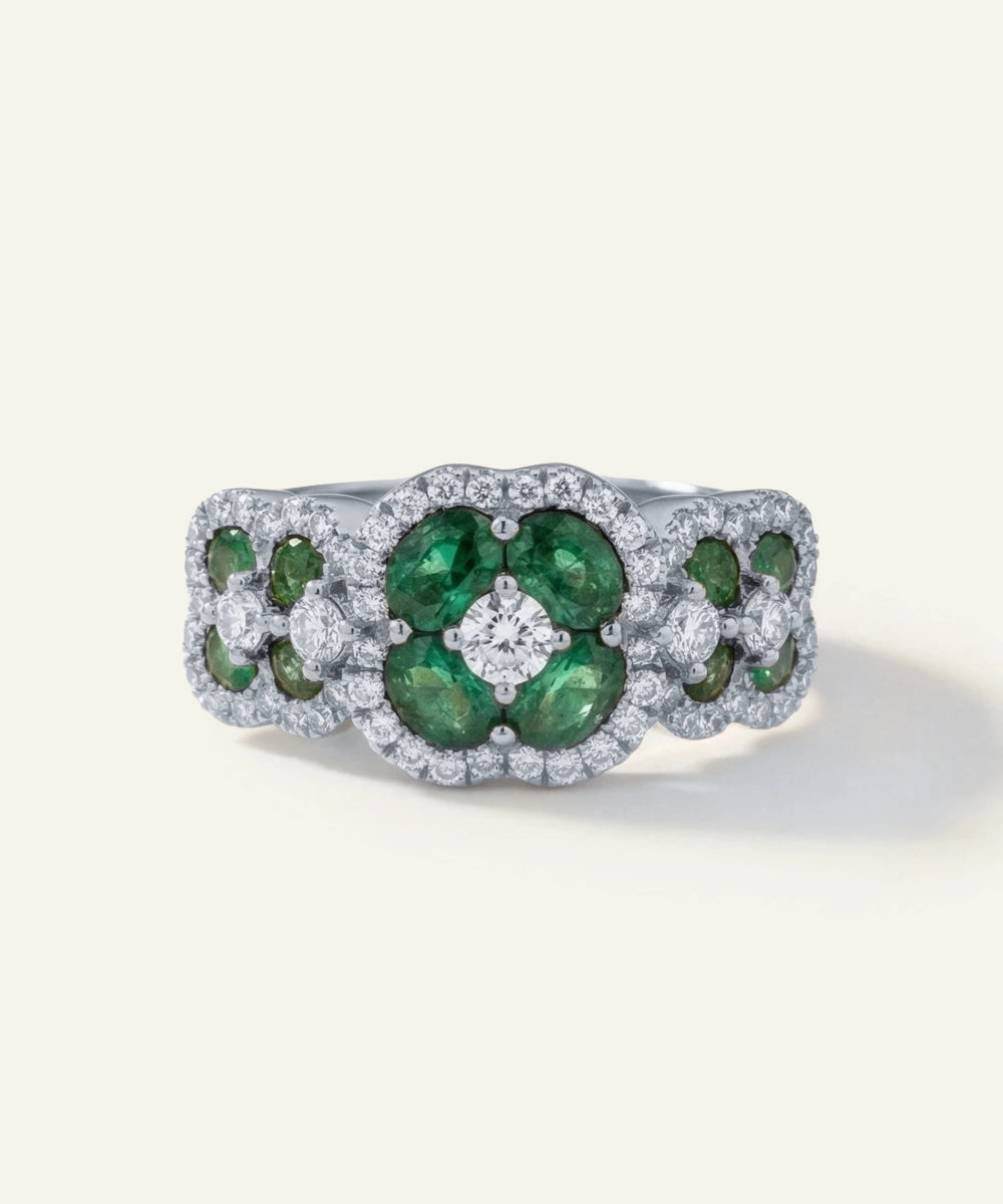 Ring with green gemstones and diamonds on a white background
