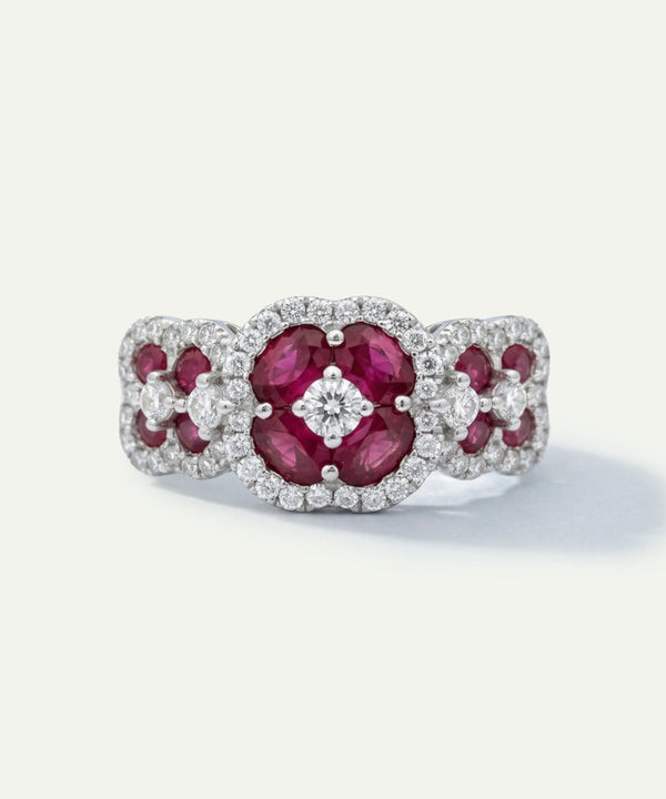 Elegant ring with red gemstones and diamond accents on a white background