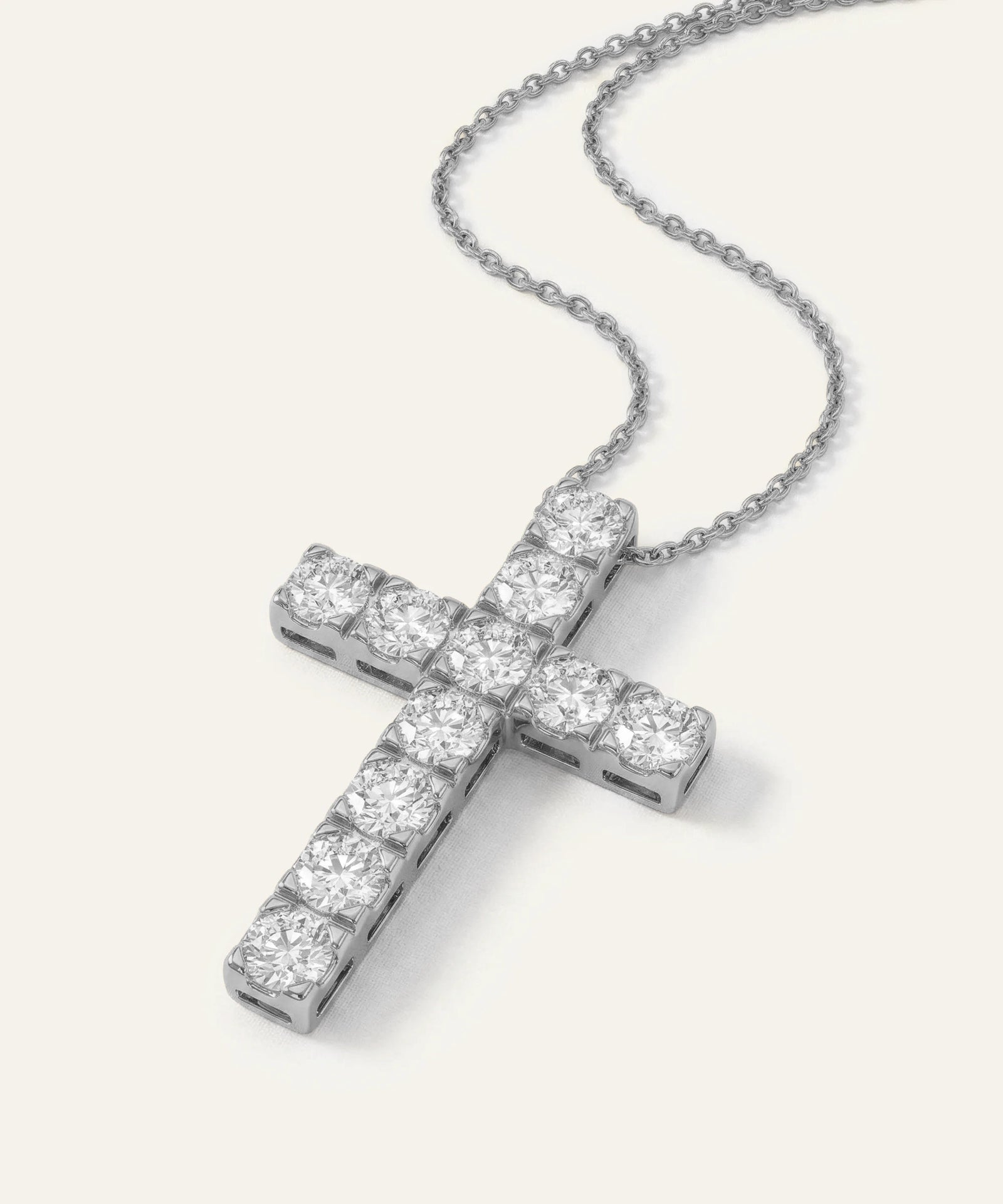 Diamond cross pendant on a chain against a white background
