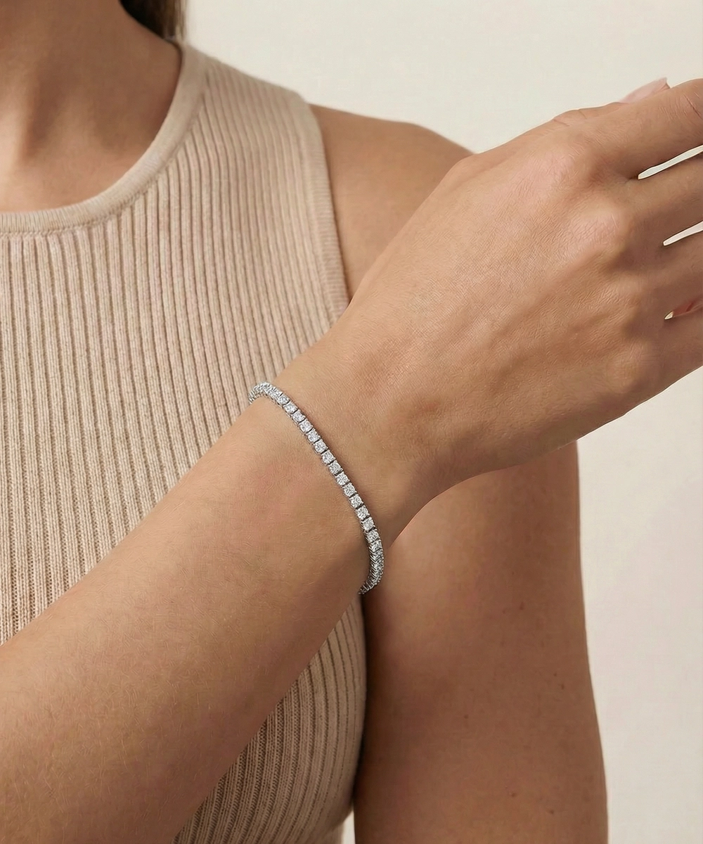 Person wearing a silver bracelet on a neutral background