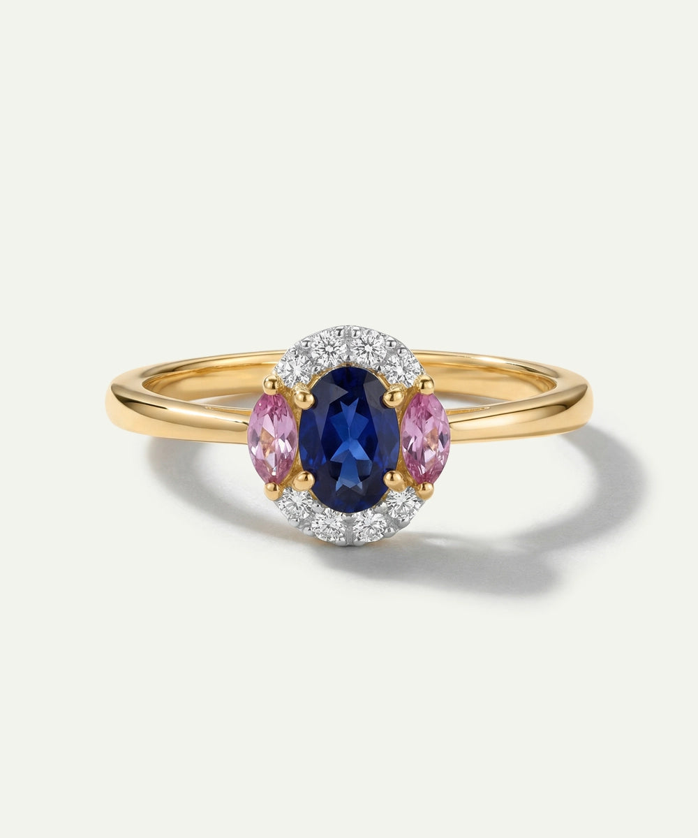 Gold ring with a blue gemstone and pink sapphires on a white background
