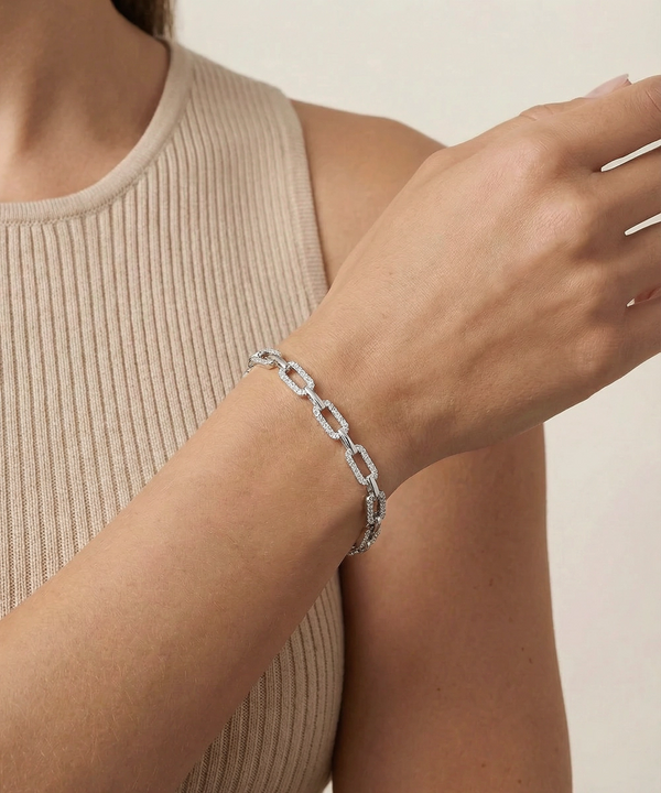 Silver chain bracelet on a person's wrist with a neutral background